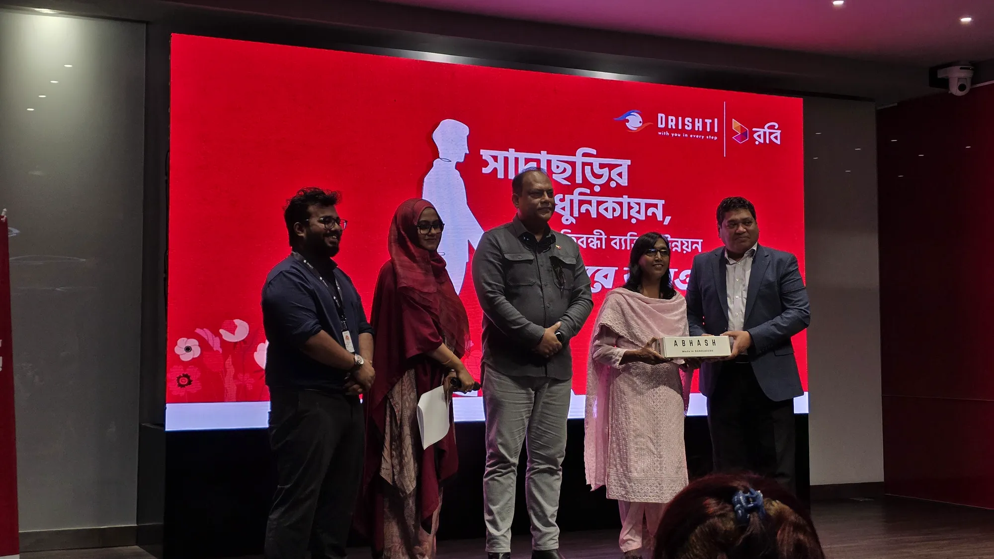 Drishti and Robi representatives handing over an Abhash device at the launch event